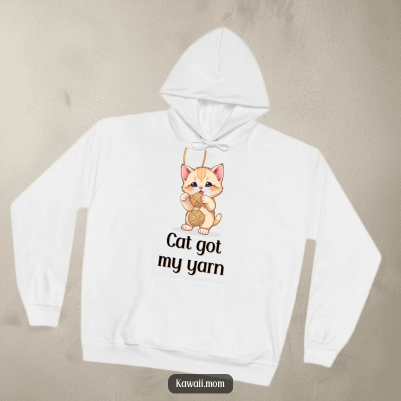 Funny cute kitten playfully batting at a dangling yarn ball on a soft and warm hoodie, a delightful gift.